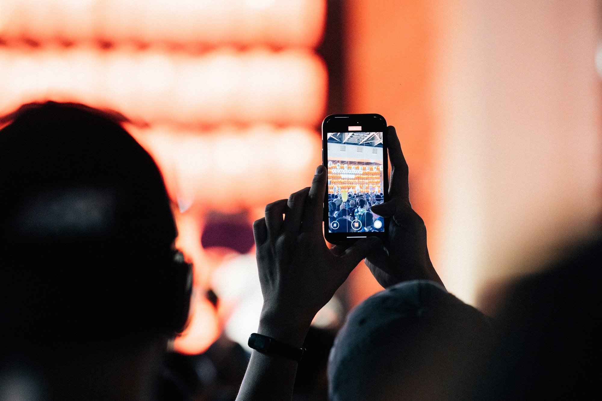An attendee holding up a phone to capture a talk on stage
