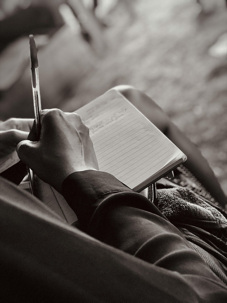A hand writing notes in a small notebook