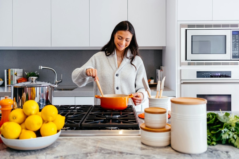 A woman stirring a pot while cooking in a bright kitchen