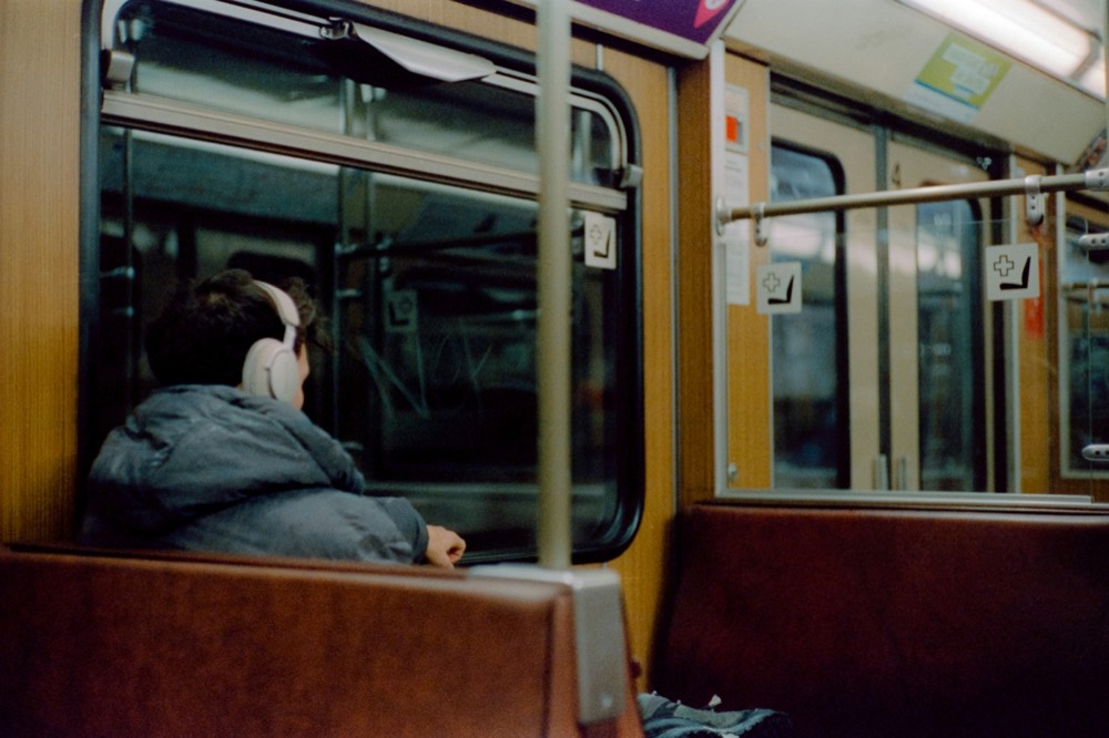 A commuter in headphones looking out a train window