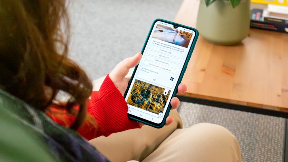 A hand holding a phone showing a long feed of articles