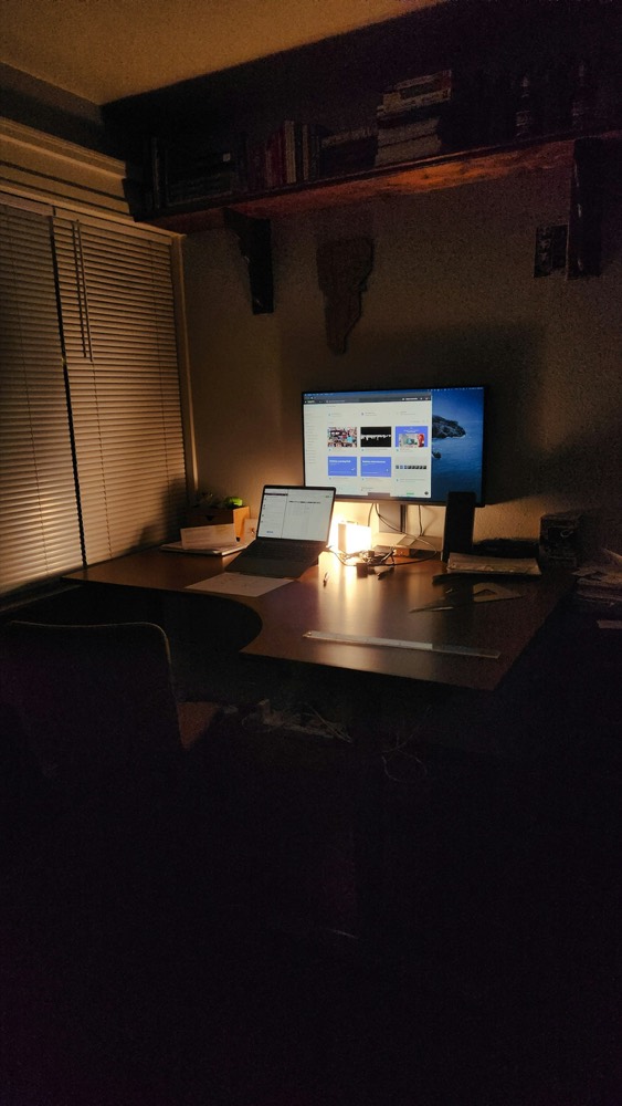 A dimly lit desk with a glowing monitor late at night